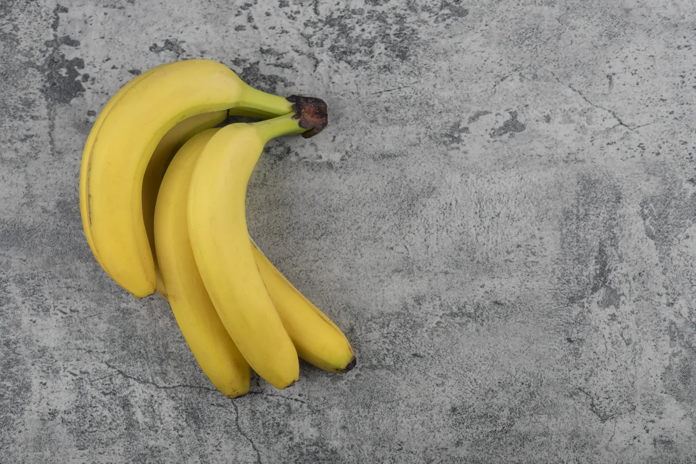 Kiść dojrzałych żółtych bananów na kamiennym blacie